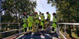 Högupplöst bild av "Yh-studerande och utbildare står på taket på liftmotorvagnen och arbetar med kontaktledningstråden", visa i nytt fönster