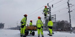 Högupplöst bild av "Järnvägstekniker i snölandskap där några står på marken och någon är på hög höjd och arbetar med kontaktledningen.", visa i nytt fönster