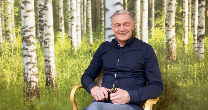 Tony Helm framför en vägg med björkskog.
